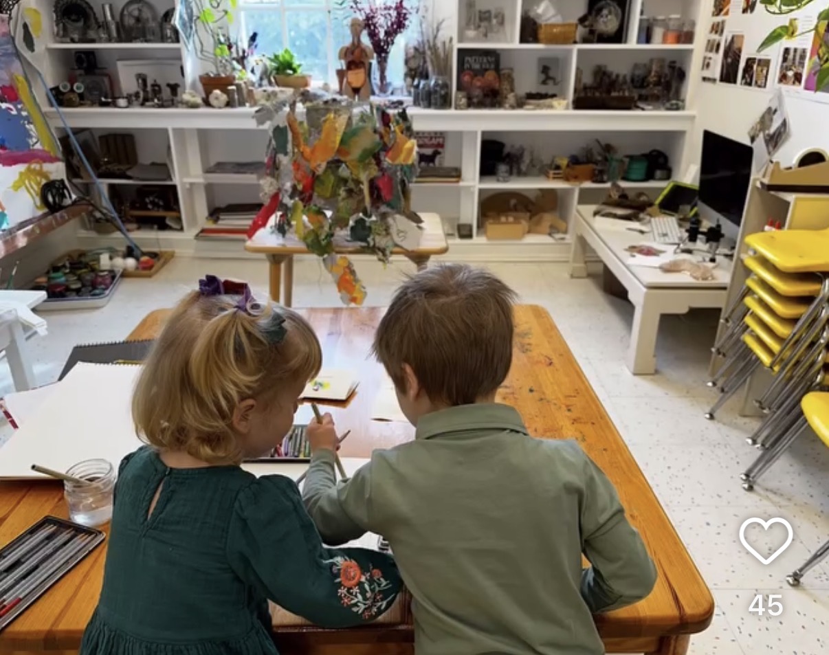 Two young children drawing together at a table in a classroom art studio